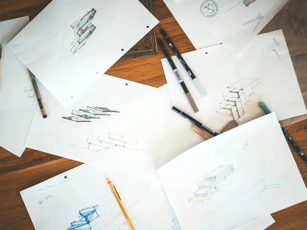 Pencil sketches and pens spread across a timber desk