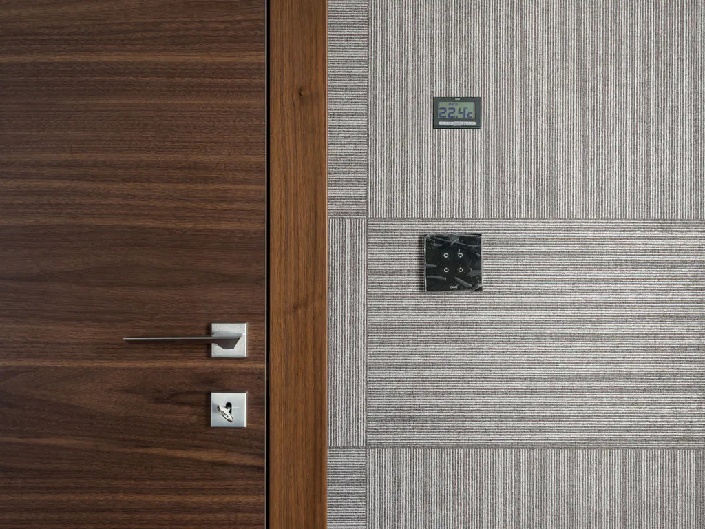 A walnut front door beside a textured wall with a slim temperature display and a touch switch