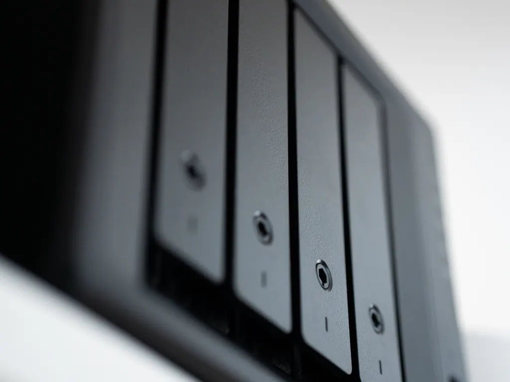 Close-up of the drive bays on a small storage server against a white wall
