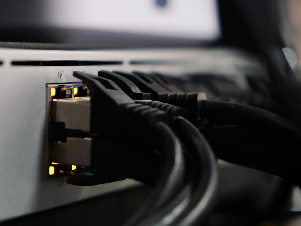 Network cables plugged into the ports of a small server, lit by amber status lights